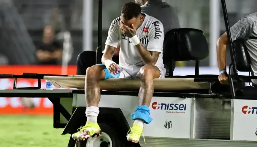 Neymar siedzi na wózku, zakrywając twarz dłońmi. Wygląda na to, że jego **neymar kontuzja** jest poważna.