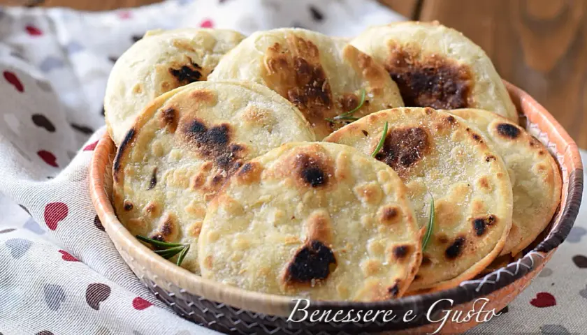 Focaccia senza lievito dorata e fragrante, servita in un cestino, con rosmarino e sale grosso. Perfetta per un pasto veloce e gustoso.