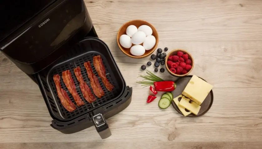 Krispigt bacon i airfryer, redo för en god frukost med ägg, bär och ost.