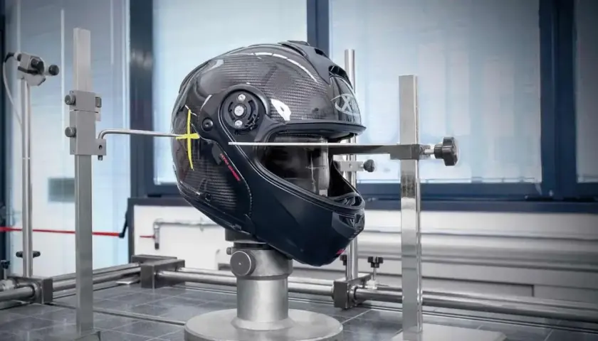 Casco in prova su banco per capire se un casco è omologato. Strumenti di misurazione puntano il guscio in carbonio.