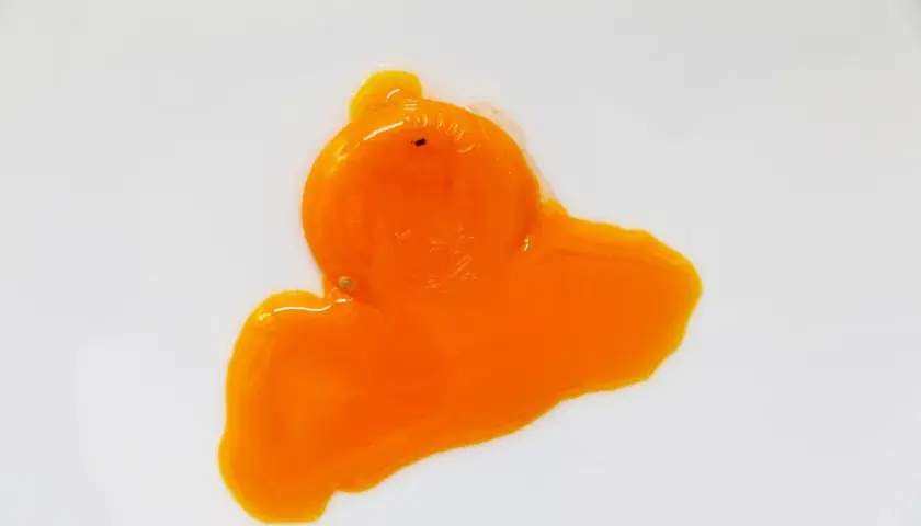 Un œuf rouge, éclatant sur une surface blanche, sa texture liquide et vibrante évoque une œuvre d'art abstraite.