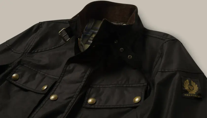Chaqueta Belstaff negra, lista para limpiar en casa. Detalles de bolsillos, cremallera y logo dorado.