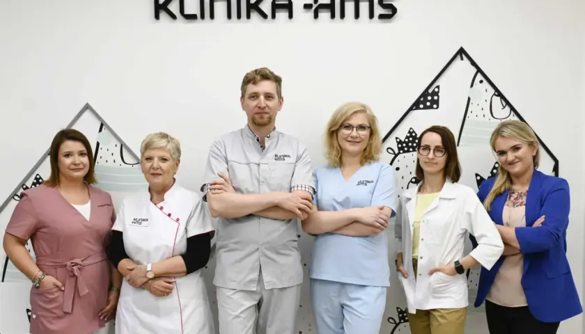 Zespół medyczny Kliniki HMS w Zielonej Górze: sześć osób w strojach medycznych i garniturze.