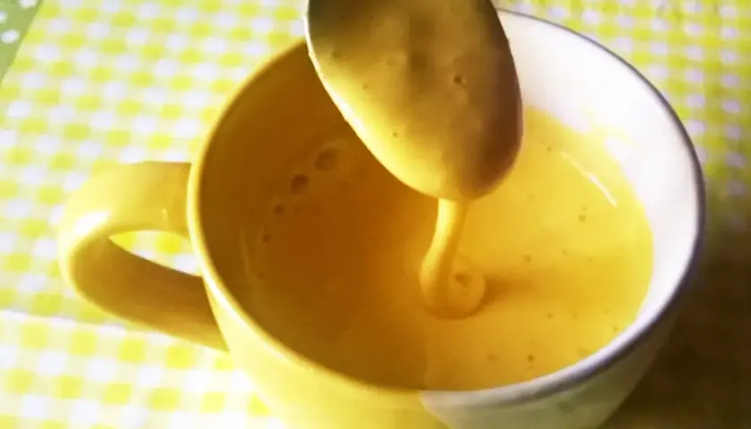 Gęsty, żółty kogel mogel spływa z łyżki do kubka. Idealny przepis na szybki deser.
