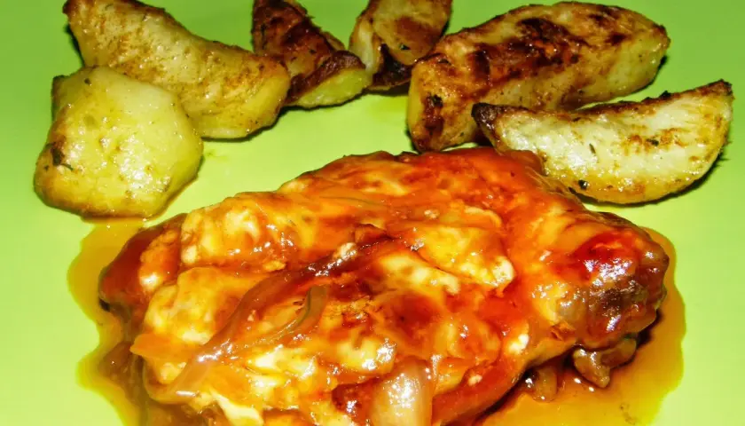 Karkówka pieczona w plastrach z majonezem i ketchupem, podana z pieczonymi ziemniakami. Pyszne danie na obiad.