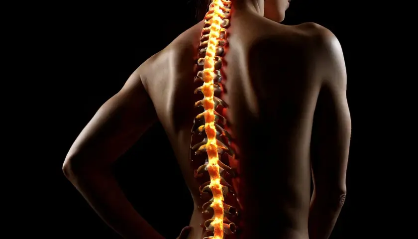 Płonący kręgosłup kobiety, symbolizujący bóle i potrzebę diagnostyki w kinezyterapii i masażu.
