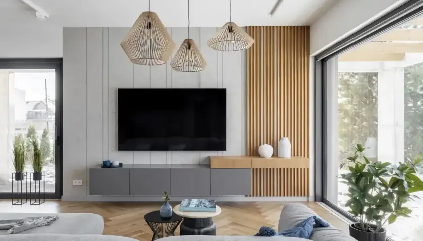 Nowoczesny salon z szarymi meblami i drewnianymi panelami. Trzy wiszące lampy tworzą przytulną atmosferę, idealną do relaksu. Zastanawiasz się, ile lumenów do salonu?