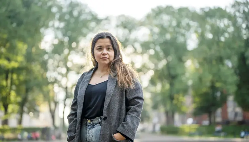 Caroline Ringskog Ferrada-Noli, partner, står utomhus i en park med träd i bakgrunden.