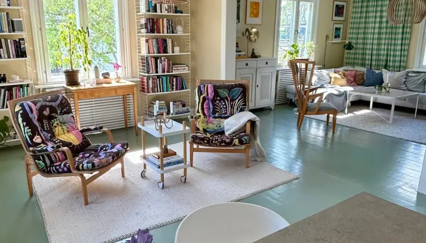 Ljust och inbjudande vardagsrum med bokhyllor, färgstarka fåtöljer och en soffgrupp. En harmonisk känsla av feng shui vardagsrum.