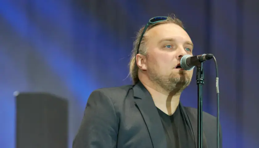 Wojciech Cugowski śpiewający do mikrofonu w czarnej marynarce.