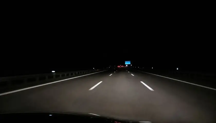 Fahrt über die Autobahn nachts. Scheinwerfer beleuchten die Fahrbahn, weiße Linien weisen den Weg in die Dunkelheit.