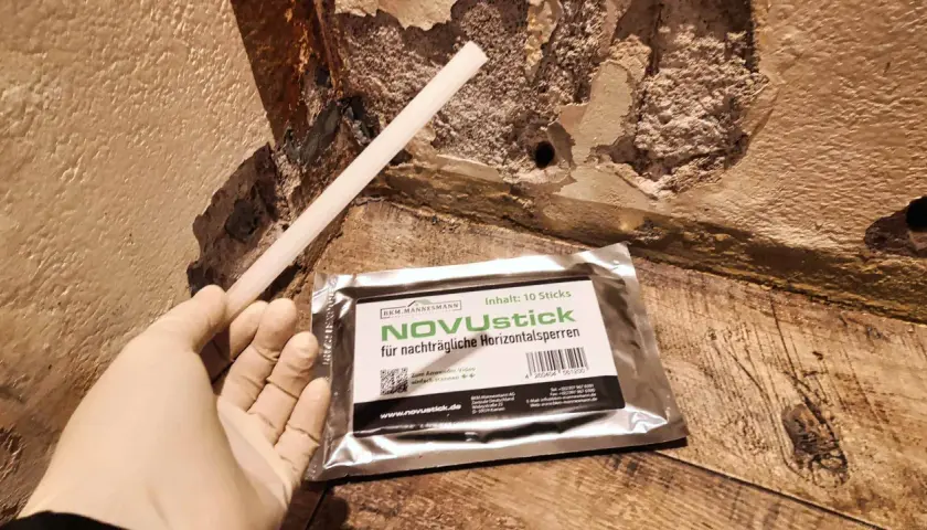 Ein Handschuh hält einen Stab für nachträgliche Horizontalsperren. Das Injektionsverfahren selber machen ist mit NOVUstick einfach.