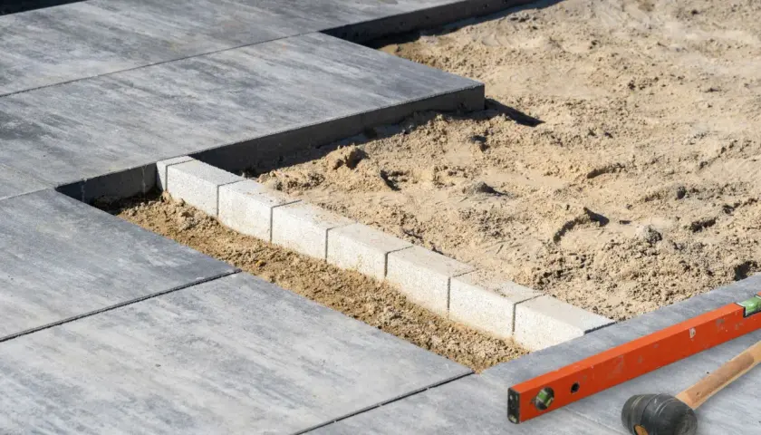 Budowa tarasu: układanie płyt betonowych, obrzeża i narzędzia budowlane.