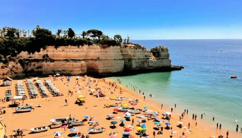 Playa con gente disfrutando del sol y el mar. Un día perfecto para actividades en el Algarve.
