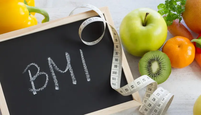 Tablica z napisem BMI, miarka krawiecka i świeże owoce. Zastanawiasz się, ile powinnaś ważyć w ciąży?