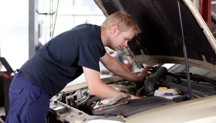 Mężczyzna pracuje przy silniku samochodu, ucząc się na kursie mechanika samochodowego dla dorosłych.