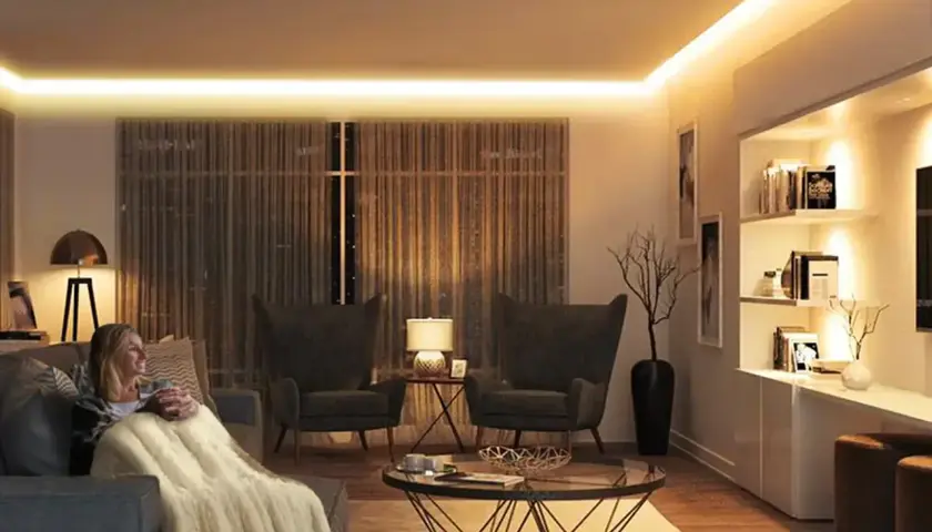 Mujer relajada en sofá con manta, rodeada de cálida iluminación ambiental de 3000k color.