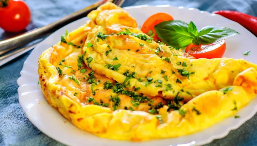 Une omelette dorée et moelleuse, garnie de persil frais. Une recette simple et rapide pour un repas savoureux.