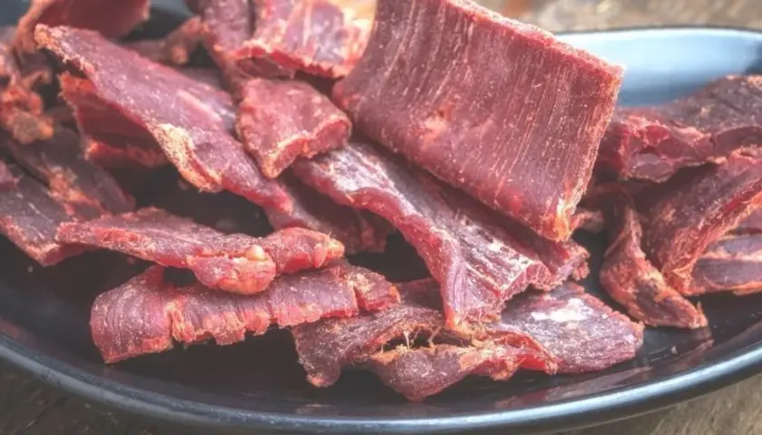 Suszone plastry mięsa wołowego na czarnym talerzu. Idealne do przekąski, gdy szukasz prostego beef jerky przepis.