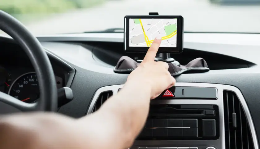 Dłoń dotyka ekranu nawigacji samochodowej, która pokazuje mapę. To najlepsza nawigacja samochodowa na telefon, która ułatwia podróż.