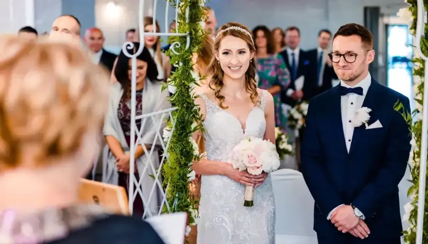 Para wzięła ślub cywilny po rozwodzie. Panna młoda w białej sukni z bukietem, pan młody w granatowym garniturze.
