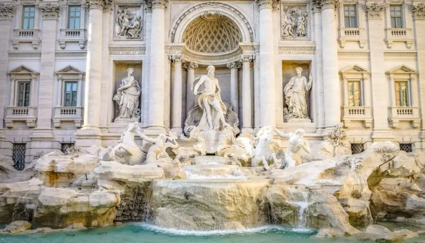 Fontana di Trevi: maestosa opera barocca con Nettuno al centro, cavalli marini e cascate d'acqua. Una descrizione iconica di Roma.