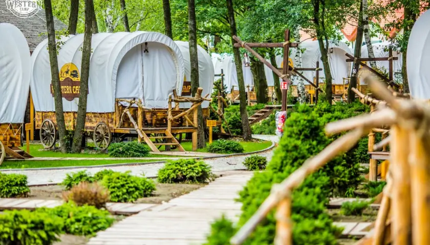 Wagony kempingowe w stylu western, idealne na wyjazd gdzie z dzieckiem w Krakowie. Drewniane ścieżki i bujna zieleń tworzą magiczny klimat.