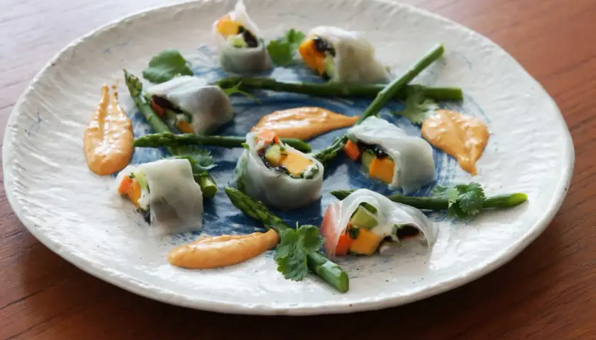 Sommarfräscha rullar med grönsaker och mango, serverade med en krämig sås. Rispapper är glutenfritt och perfekt för dessa lätta rullar.