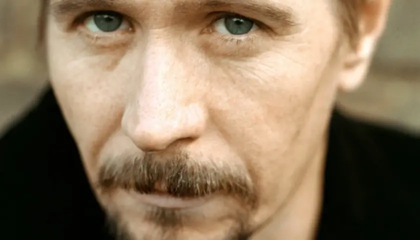 Młody Gary Oldman z przenikliwym spojrzeniem i charakterystycznym wąsikiem.