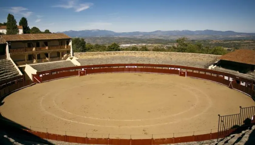 La plaza de toros El Castañar, con su arena de arena y gradas de piedra, se alza majestuosa ante un paisaje montañoso.
