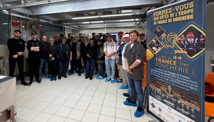 Une équipe de bouchers pose devant une bannière "Équipe de France Boucherie". Une idée de préparation boucherie pour le championnat du monde.