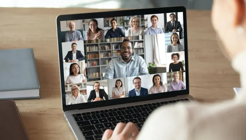 Ein Team bespricht sich per Videoanruf. Viele Gesichter lächeln vom Laptop-Bildschirm, was die Flexibilität von jobs im home office zeigt.