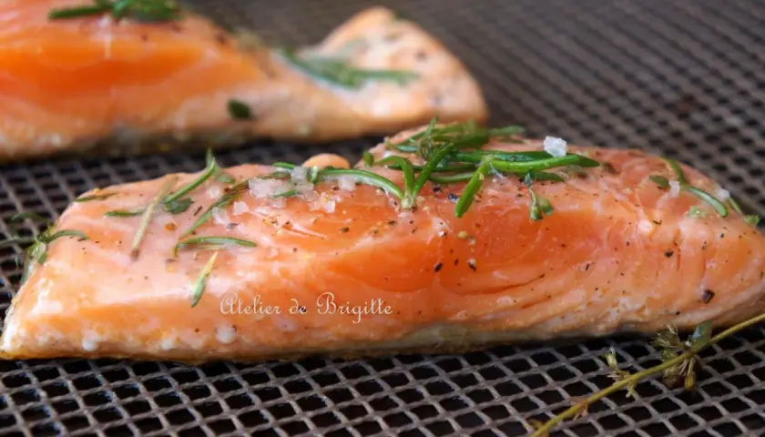 Filets de saumon sur une grille, assaisonnés de sel, poivre et romarin. Parfait pour une cuisson plancha à la bonne température.
