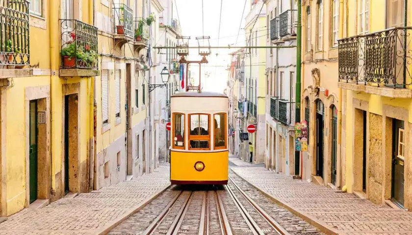 A classic yellow tram ascends a steep, cobblestone street lined with colorful buildings, a perfect scene for one day in Lisbon.