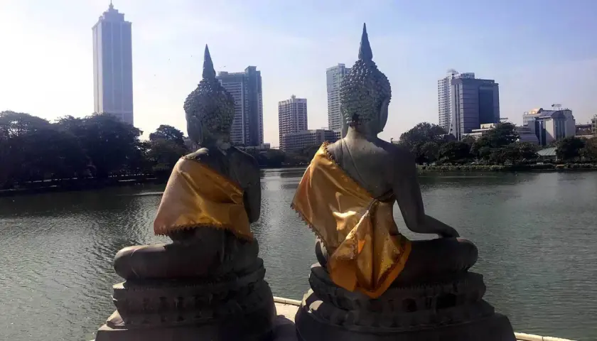 Dwie posągi Buddy z widokiem na nowoczesną panoramę stolicy Sri Lanki.