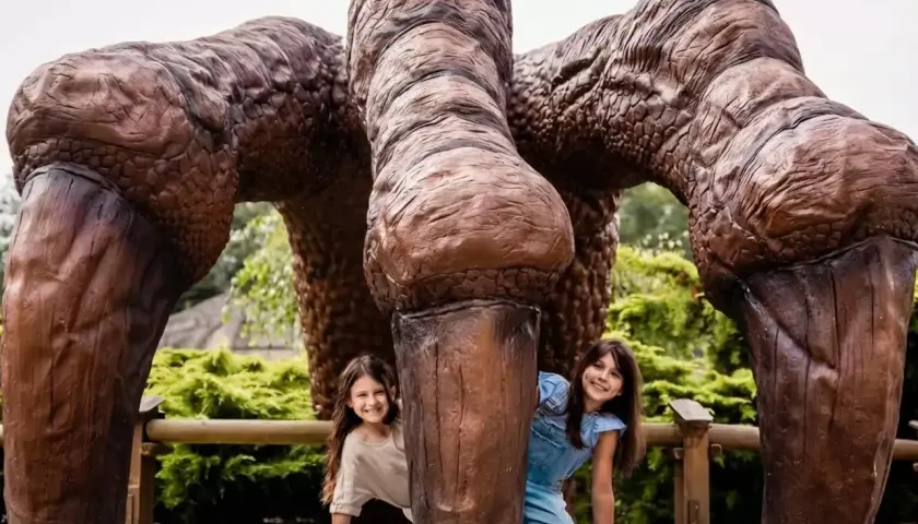 Dwie dziewczynki ukrywają się za gigantycznymi łapami dinozaura. Wspaniałe lublin atrakcje dla dzieci!
