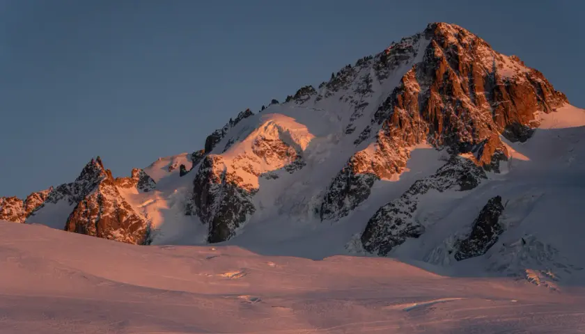 Ośnieżone szczyty Alp o wschodzie słońca, oświetlone złotym blaskiem. Widok na trasę Haute Route, gdzie lodowce i skaliste zbocza tworzą majestatyczny krajobraz.