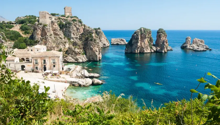 A picturesque bay with turquoise waters, rocky islets, and a historic tower, showcasing one of the most beautiful places in Sicily.