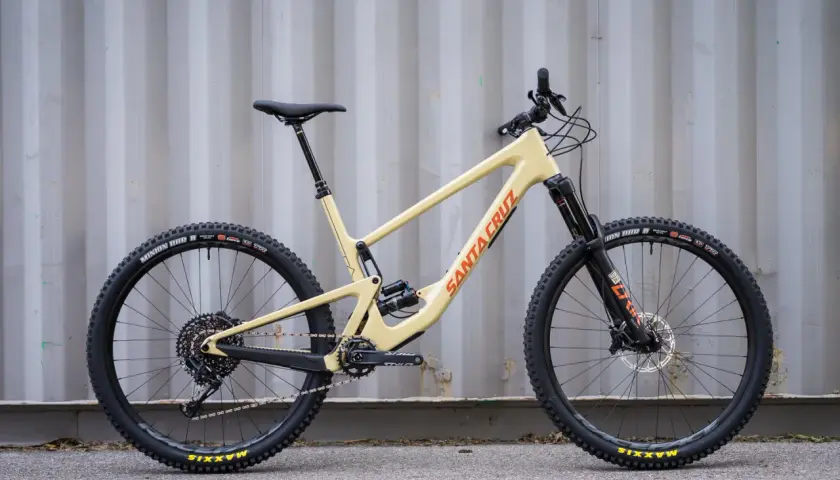 A tan 2020 Santa Cruz Hightower mountain bike with black wheels and orange "Santa Cruz" lettering.