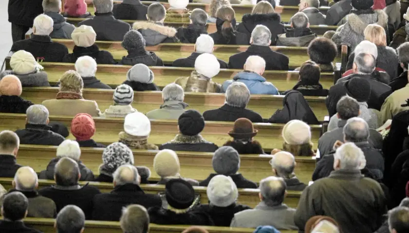 Ludzie siedzą w kościele, zastanawiając się, ile kosztują msze gregoriańskie. Wszyscy ubrani są ciepło, przygotowani na zimno.