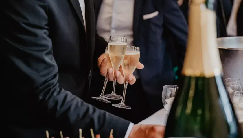 Des flûtes de champagne pétillant pour le vin d'honneur mariage. Des canapés colorés et une bouteille de champagne en avant-plan.