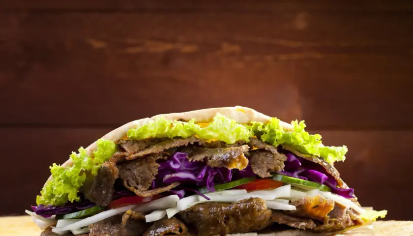 Kebab z mięsem, sałatą, czerwoną kapustą i warzywami w picie.