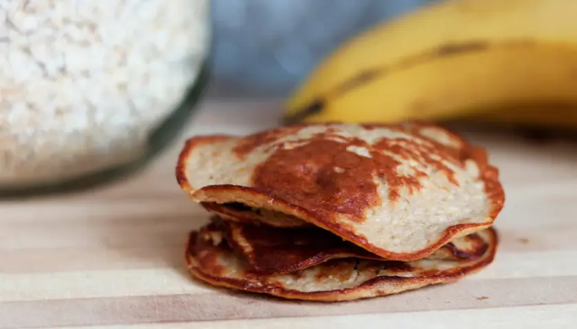 En hög med gyllenbruna bananpannkakor, redo att avnjutas. Ett enkelt bananpannkaka recept för en god frukost.