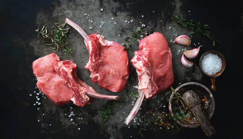 Trois belles côtes de veau crues, prêtes à être assaisonnées avec du sel, de l'ail et des herbes aromatiques.