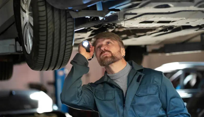 Mechanik bada podwozie auta, szukając uszkodzone jarzmo zacisku objawy.