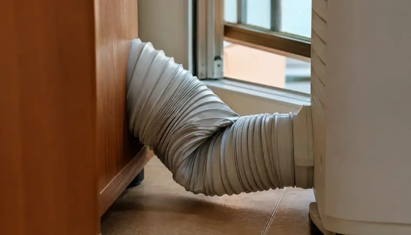 El tubo de un aire acondicionado portátil, conectado a una ventana, parece un poco torcido. ¡Espero que mi pinguino no enfria!