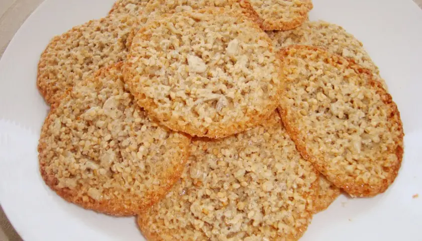 En hög med krispiga, gyllene glutenfria havreflarn på en vit tallrik. Perfekta för fikat!