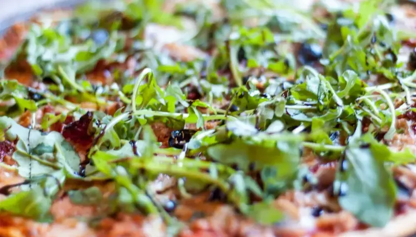 Pyszna pizza z tuńczykiem, rukolą i oliwkami, polana sosem balsamicznym. Idealna na szybki obiad.