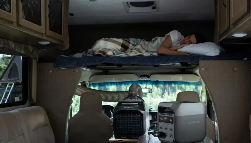 Un homme dort dans un camping-car 4 places. Une unité de climatisation portable et une station d'énergie sont visibles.