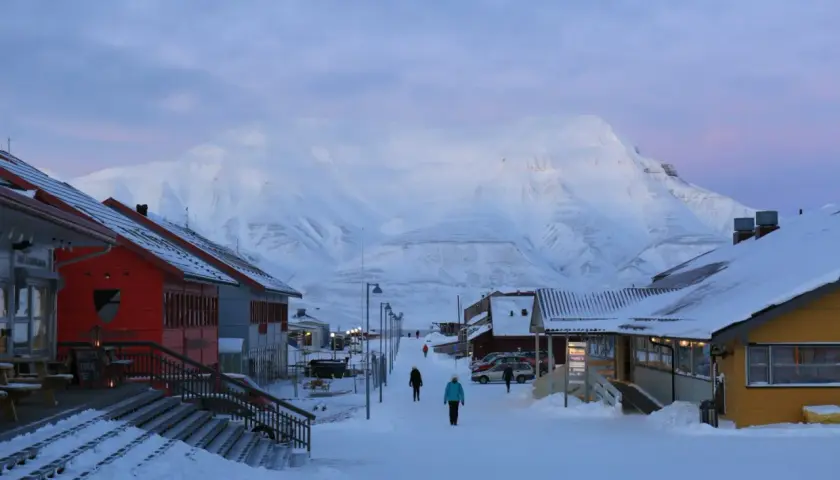Śnieżna ulica w Longyearbyen, najwyżej położonym mieście na świecie, z górami w tle.